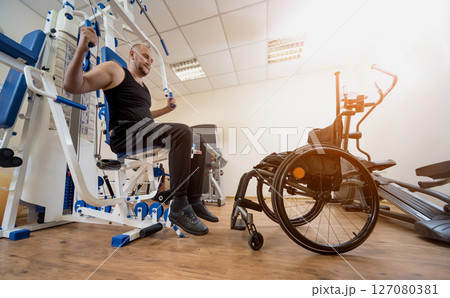 Disabled man doing strength exercises separate from the wheelchair. Disabled man doing strength exercises separate from the wheelchair. 127080381