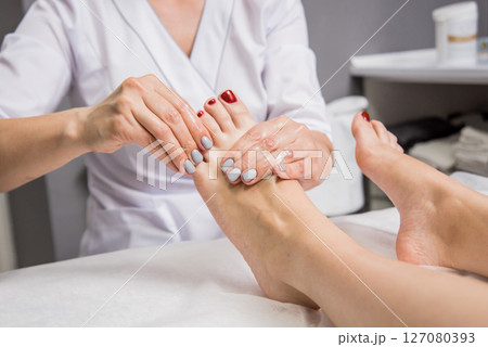 Beautiful young woman enjoying foot massage in spa salon. Cosmetology 127080393