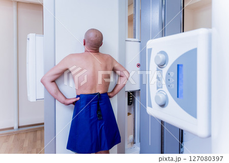 Radiologist and patient in a x-ray room. Classic ceiling-mounted x-ray system. 127080397