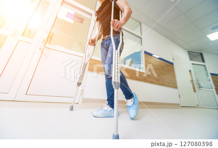 Injured man trying to walk on crutches in the hospital. 127080398