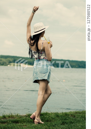 The girl is standing with her face turned to the lake and her back to the camera The girl is standing with her face turned to the lake and her back to the camera 127080522