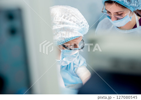 Surgeon and assistants in operating room with surgery equipment. Surgeon and assistants in operating room with surgery equipment. 127080545