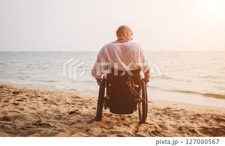 Disabled man in a wheelchair on the beach. Disabled man in a wheelchair on the beach. 127080567