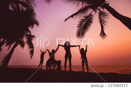 Disabled man in a wheelchair with his family on the beach. Silhouettes at sunset 127080572