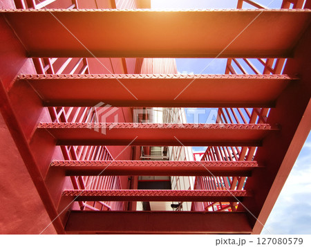 A set of stairs ascending a large red wall 127080579