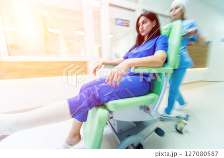 Nurse moves mobile medical chair with patient at hospital. Medical equipment. Nurse moves mobile medical chair with patient at hospital. Medical equipment. 127080587