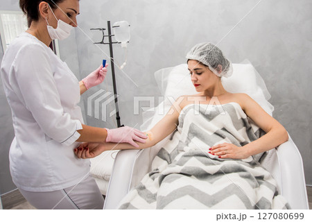 The doctor cosmetologist makes cosmetology dropper procedure. Infusion. The doctor cosmetologist makes cosmetology dropper procedure. Infusion. 127080699