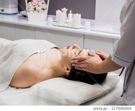 Beautiful young woman enjoying head massage in spa salon. Cosmetology 127080804