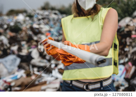 Woman volunteer helps clean the field of plastic garbage.  127080811