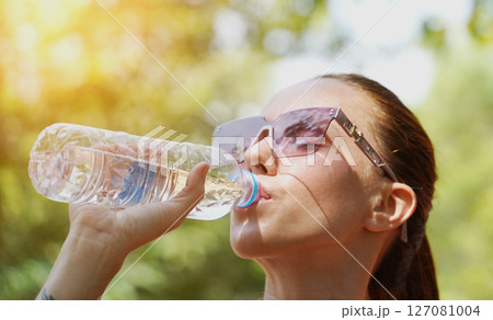 A man and a woman drinking refreshing water from bottles after jogging together in a park A man and a woman drinking refreshing water from bottles after jogging together in a park 127081004
