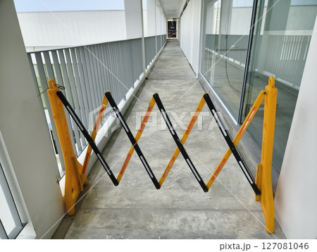 A bright yellow and dark black barrier is in the center of a hallway 127081046