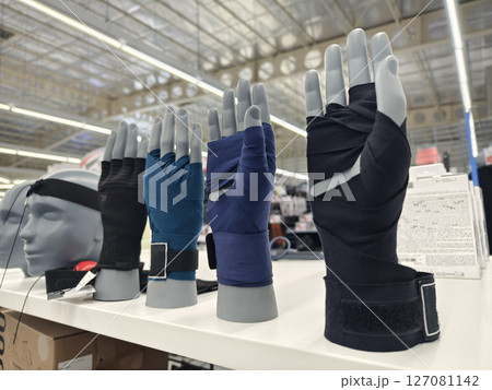 A store features an impressive display of sport gloves on mannequins 127081142