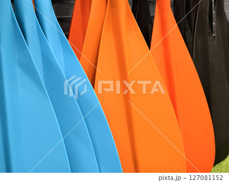 A collection of oars is lined up neatly in a row for use 127081152