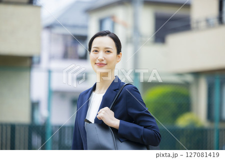住宅街を歩くスーツを着た若い女性 住宅街を歩くスーツを着た若い女性 127081419