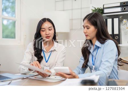 Collaborative Strategy Session. Two women discussing project plans at office table. 127081504