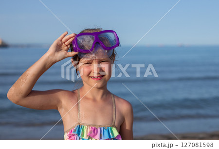 Toddler girl with purple snorkeling goggles at the beach on a sunny day 127081598