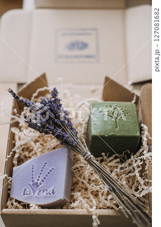 Lavender and olive oil soaps with dried flowers in a kraft gift box filled with shredded filler. Botanical skincare, handmade soap, natural ingredients, eco-conscious packaging Lavender and olive oil soaps with dried flowers in a kraft gift box filled with shredded filler. Botanical skincare, handmade soap, natural ingredients, eco-conscious packaging 127081682