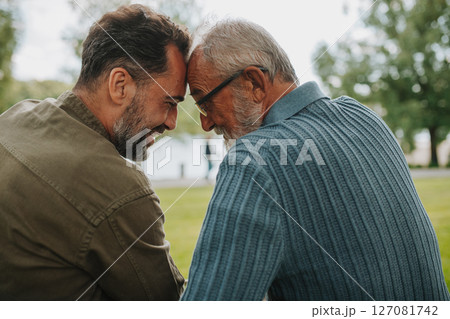 Father and adult son sharing a peaceful moment, touching with foreheads. Father and adult son sharing a peaceful moment, touching with foreheads. 127081742