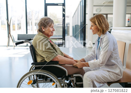 Elderly patient in wheelchair talking with female physician. 127081822