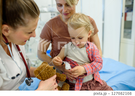 Doctor and young toddler patient treat a teddy bear. 127082108