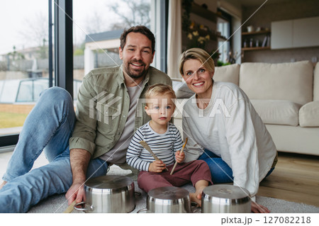 Parents and toddler son playing drums on kitchen pots Parents and toddler son playing drums on kitchen pots 127082218