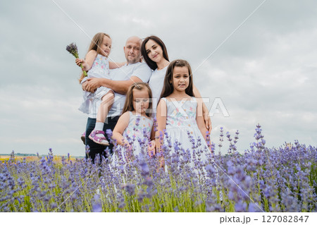 A young mother looks tenderly at her beautiful daughters in a field of lavender A young mother looks tenderly at her beautiful daughters in a field of lavender 127082847