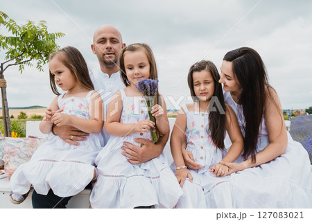 A close-knit family sits on a beautiful bench in a fairytale landscape A close-knit family sits on a beautiful bench in a fairytale landscape 127083021