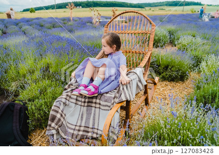 The girl is sitting in a rocking chair among the lavender 127083428