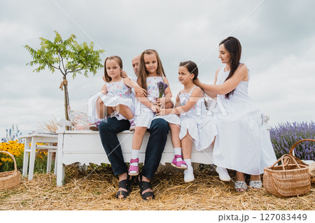 The young family sits on an old-fashioned bench in the lavender field 127083449