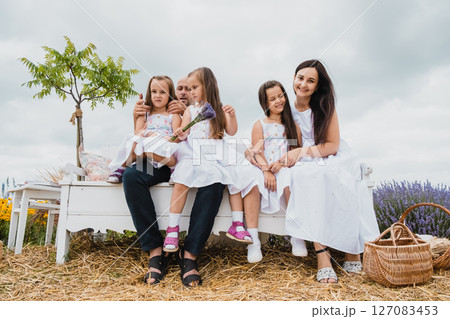 A white retro bench stands in the lavender field, where a happy family has gathered 127083453