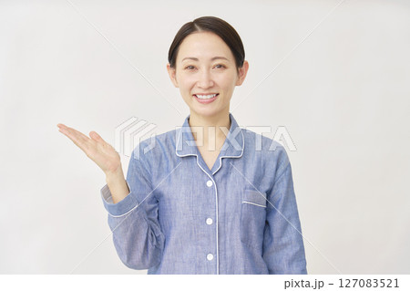 パジャマを着た女性　手のひらで左を指す　白バック 127083521