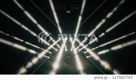 Powerful geometric light beam patterns cutting through artificial fog creating volumetric illumination at dark music venue 127083793
