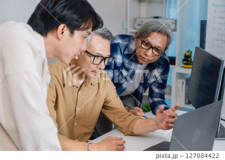 Team of developers collaborating in brainstorming and coding project at office workspace 127084422