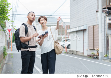 スマホ翻訳アプリで外国人に道案内する女性 127084429