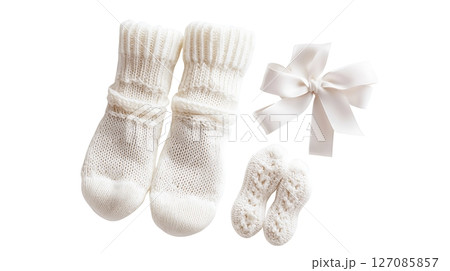 A pair of baby socks and a bow are displayed on a white background 127085857