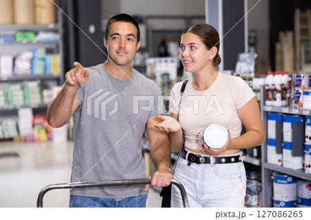 Interested couple talking while selecting painting tools in store Interested couple talking while selecting painting tools in store 127086265