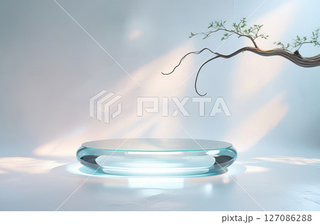 A modern minimalist setting featuring a transparent glass table with a smooth, rounded shape, set against a softly illuminated background. 127086288