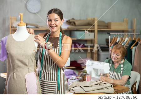 Young woman working with mannequin, elderly woman sewing 127086560