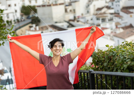 Happy latin american woman posing outdoors with national flag of Peru 127086666