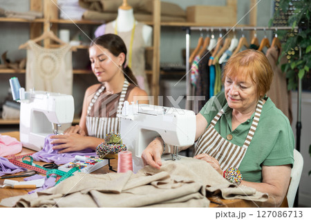 Seamstresses work on machines in a sewing workshop 127086713