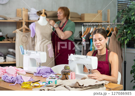 Young woman sews on machine female assistant sews on mannequin 127086985
