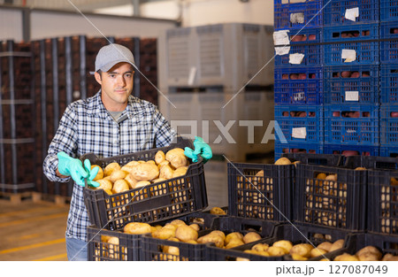 Worker stacking crates of potatoes in warehouse Worker stacking crates of potatoes in warehouse 127087049