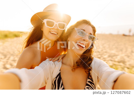 Two pretty friends women making selfie on beach, light and bright summer colors. Friends together 127087602