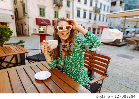 Young woman enjoying coffee at a cozy outdoor caf? in Kotor, Montenegro during a sunny afternoon 127088284