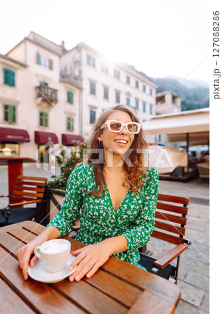 Young woman enjoying coffee at a cozy outdoor caf? in Kotor, Montenegro during a sunny afternoon 127088286