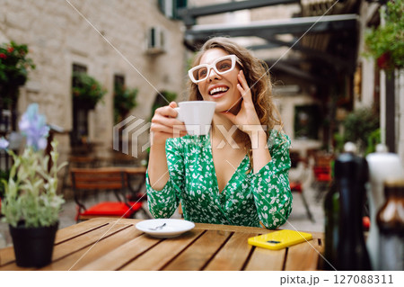 Young woman tourist drinks coffee in the old town in summer trip. People, fashion, lifestyle Young woman tourist drinks coffee in the old town in summer trip. People, fashion, lifestyle 127088311