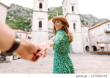 Follow me concept and traveling together. A woman in a green dress holds hands with a partner 127088338