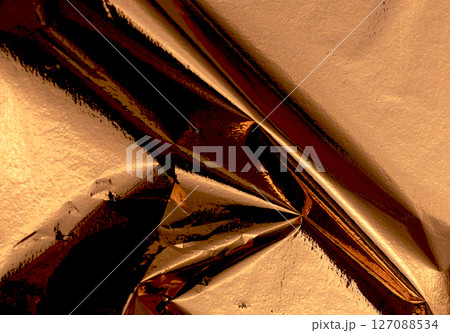 Gold and bronze metallic foil texture with a shiny, crumpled surface. Abstract, reflective pattern 127088534