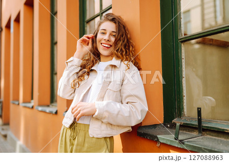 Optimistic woman with curly hair walking on the street city. Concept of lifestyle, fashion, travel. Optimistic woman with curly hair walking on the street city. Concept of lifestyle, fashion, travel. 127088963