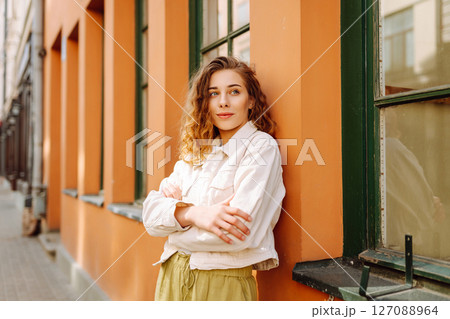 Optimistic woman with curly hair walking on the street city. Concept of lifestyle, fashion, travel. Optimistic woman with curly hair walking on the street city. Concept of lifestyle, fashion, travel. 127088964